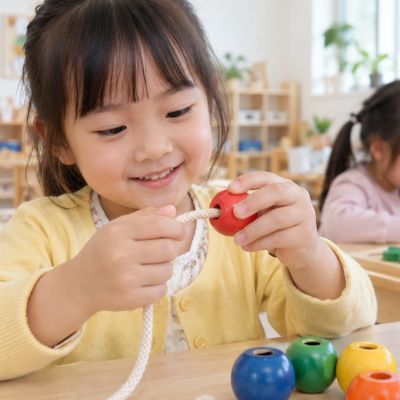 小手慢慢對準珠孔，終於穿進第一顆大木珠。