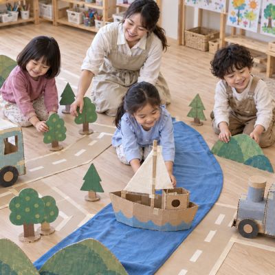 教室變成旅行路線：孩子沿著紙膠帶道路、布河與紙山布置想像路線。
