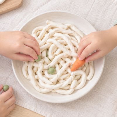 蔬菜也要排好隊：孩子替麵碗加上先前做好的紅蘿蔔與豌豆。