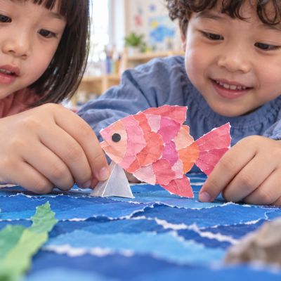 重新固定就成功：孩子用摺好的支架讓紙魚穩穩站起，從低角度看見立體效果。