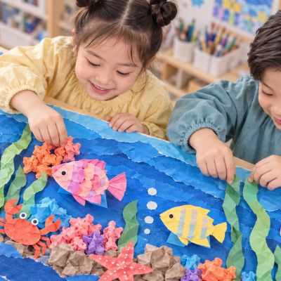 添上珊瑚與海草：孩子把皺紋紙珊瑚和綠色紙海草分層貼好，作品逐漸完成。