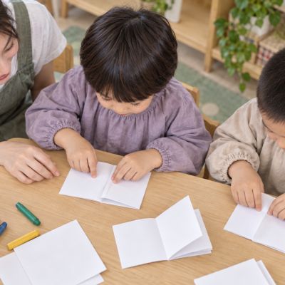 摺出一本小書：孩子把紙張對摺成冊，準備留下自己的圖畫。