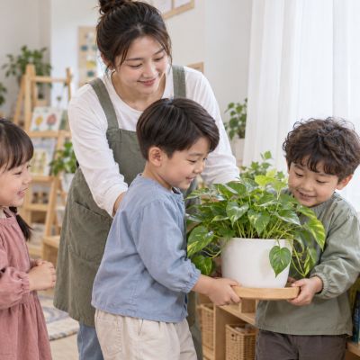 搬到舒服的窗邊：孩子合作扶著花盆與托盤，移到明亮散射光處。