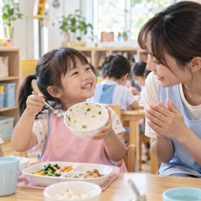 老師在一旁鼓勵，孩子開心展示自己吃得好棒。